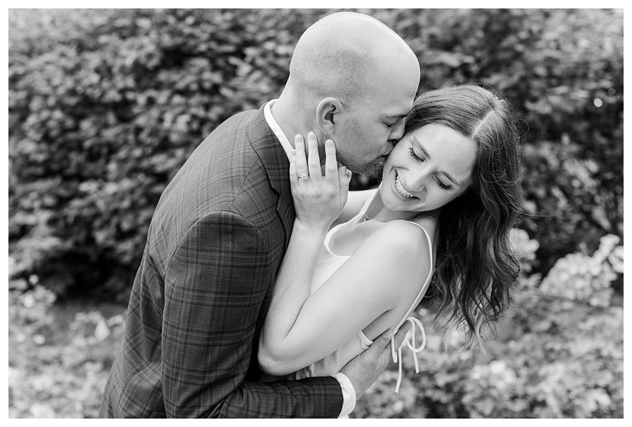 Engaged couple embracing beneath a floral arch during a Loose Park engagement session in Kansas City, Missouri